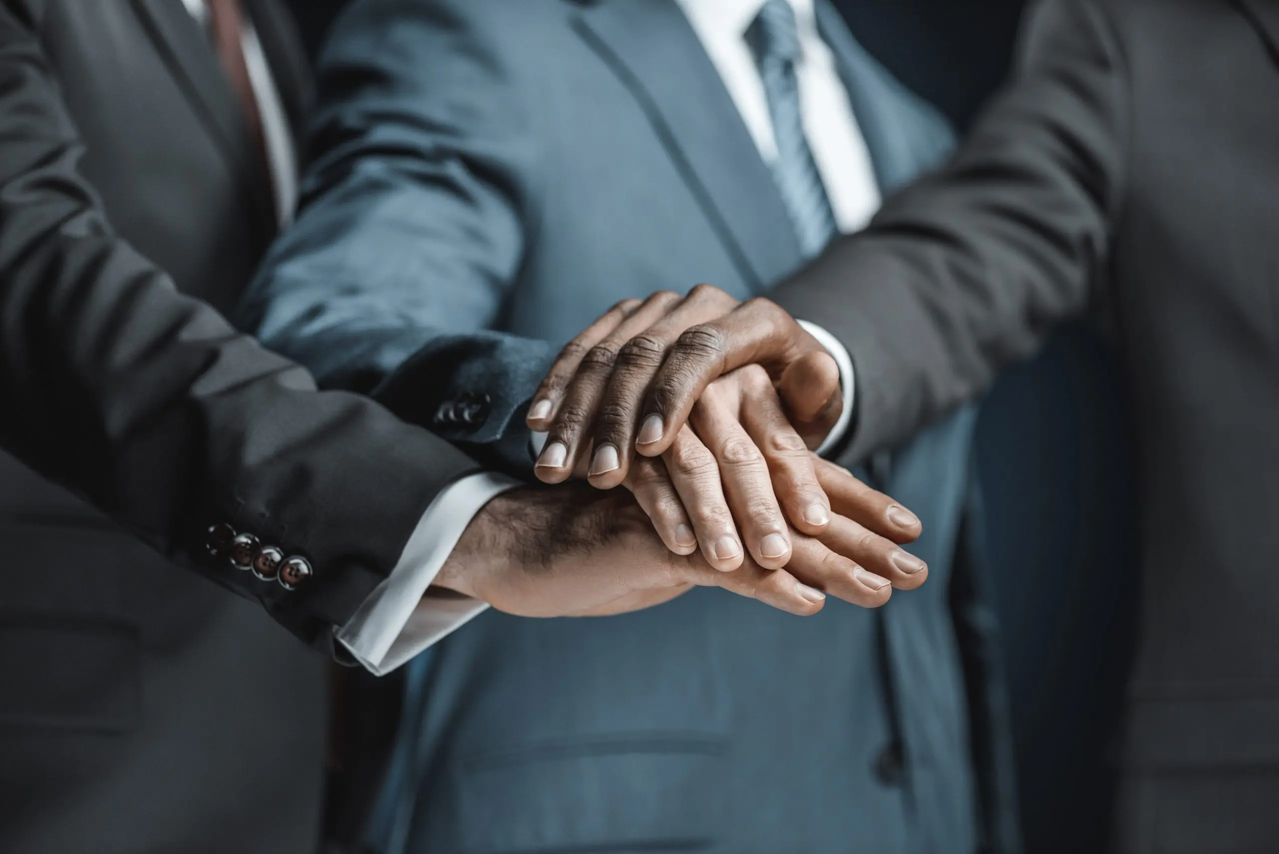 cropped shot of multiethnic group of businessmen holding hands together